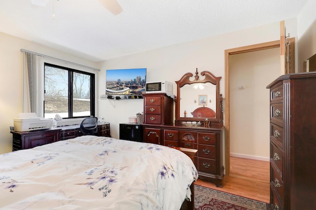 bedroom featuring a textured ceiling, baseboards, ceiling fan, and wood finished floors