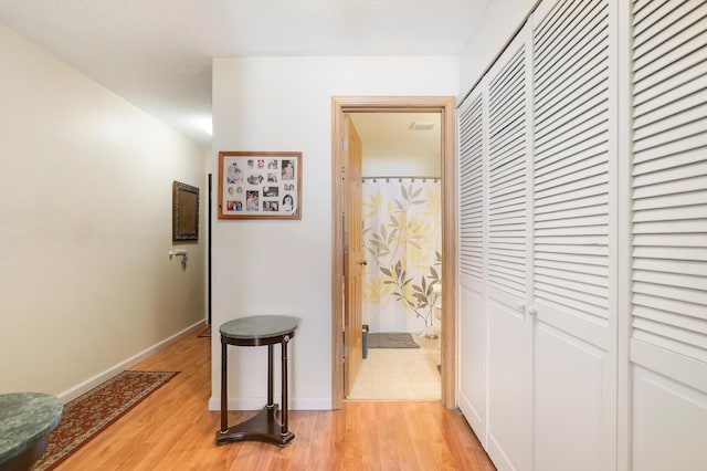 hallway featuring baseboards and light wood-style flooring