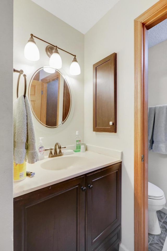 bathroom featuring toilet, vanity, and a textured ceiling