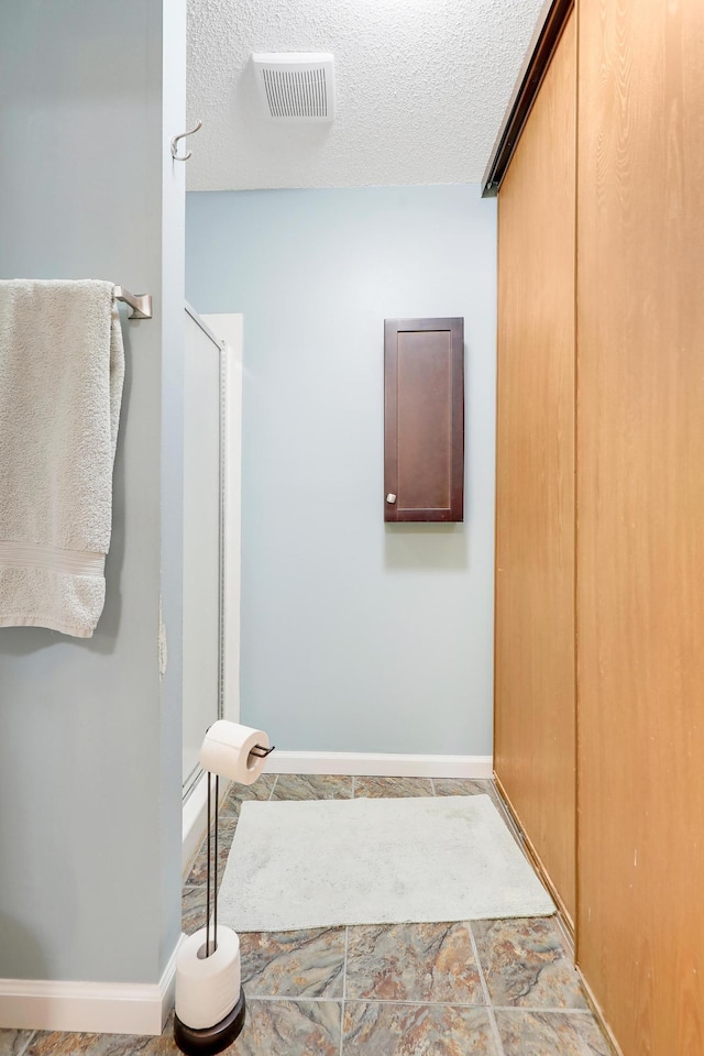 bathroom featuring baseboards, visible vents, and a textured ceiling