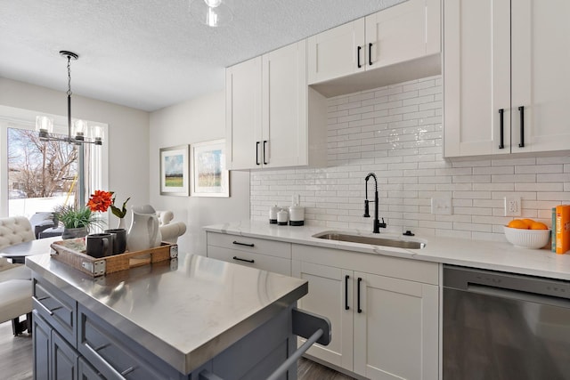 kitchen featuring white cabinets, backsplash, a textured ceiling, stainless steel dishwasher, and a sink