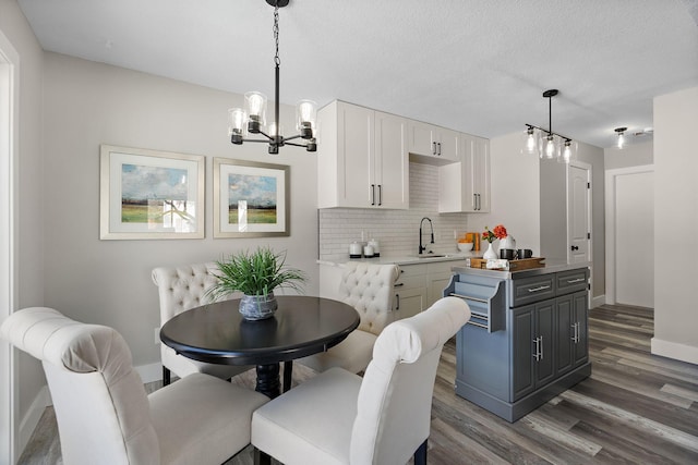 dining space featuring an inviting chandelier, a textured ceiling, baseboards, and wood finished floors