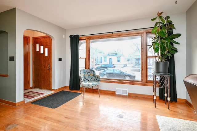 entryway featuring arched walkways, wood finished floors, visible vents, and baseboards