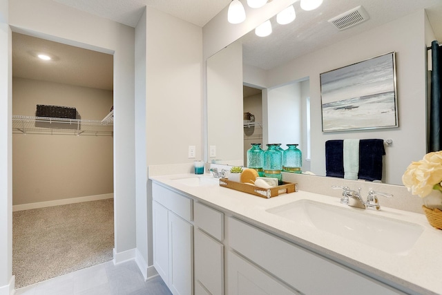 full bath with double vanity, a spacious closet, visible vents, and a sink