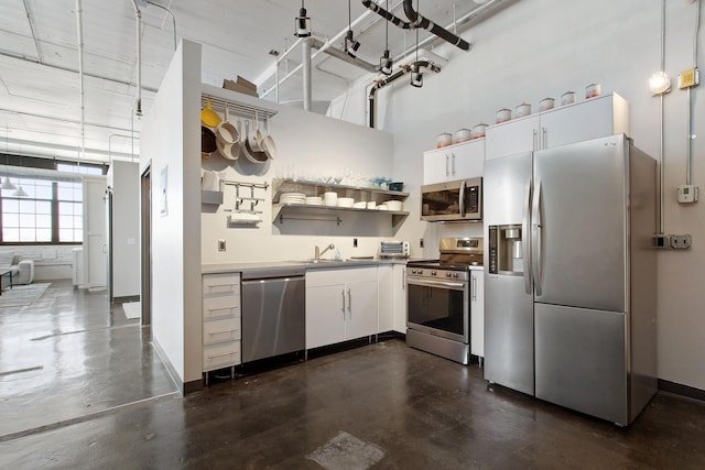 kitchen featuring a sink, a towering ceiling, baseboards, appliances with stainless steel finishes, and open shelves