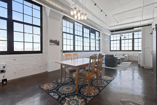 dining space with concrete flooring, brick wall, and a towering ceiling