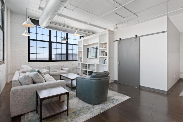 living room with finished concrete flooring, brick wall, a barn door, and baseboards