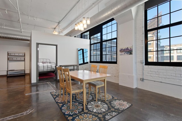 dining area with brick wall, a high ceiling, and concrete floors