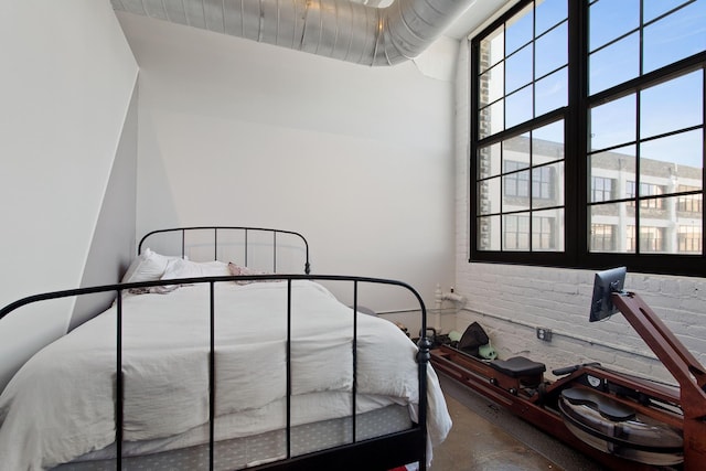 bedroom featuring concrete floors and brick wall