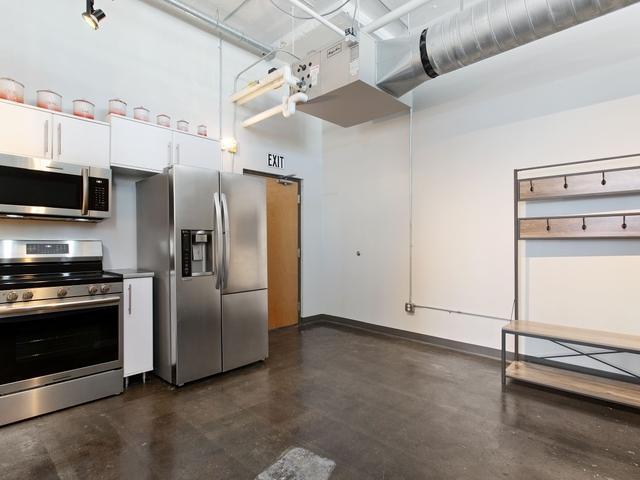 kitchen with stainless steel appliances, a high ceiling, and white cabinetry