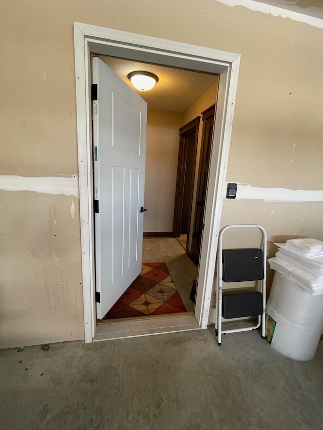 hall featuring unfinished concrete flooring