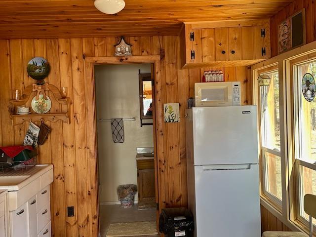 kitchen with white appliances, white cabinets, and wood walls