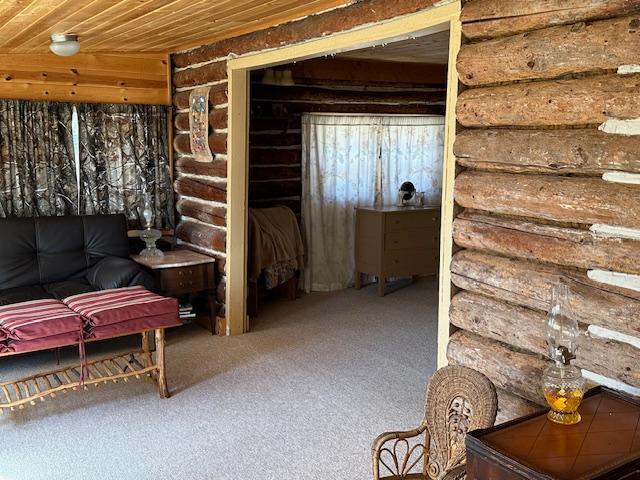 interior space with log walls, carpet floors, and wood ceiling