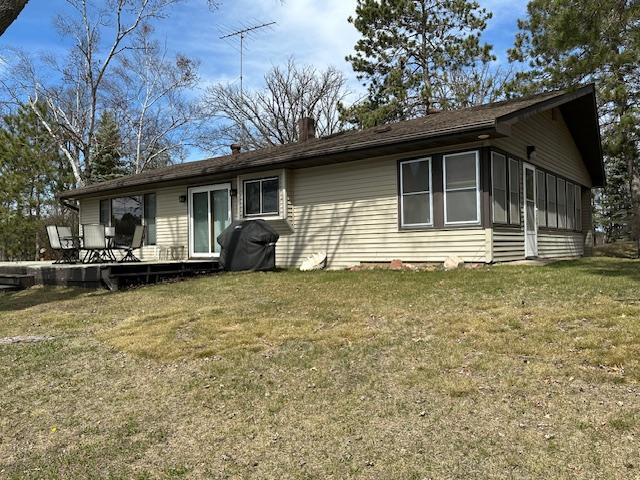 ranch-style house with a chimney, a deck, and a front yard