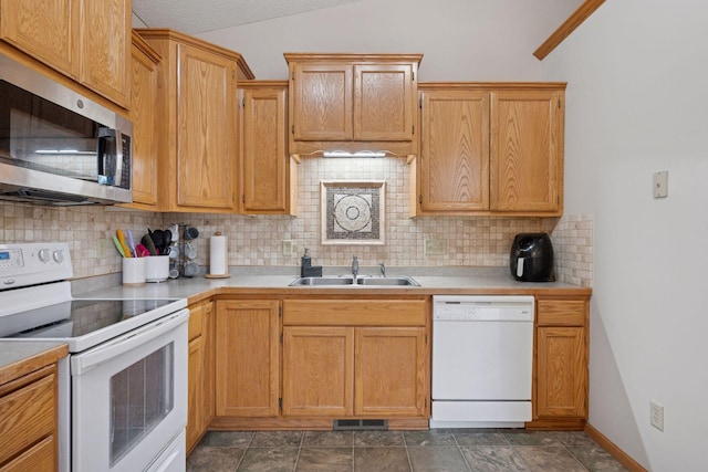 kitchen with decorative backsplash, white appliances, light countertops, and a sink