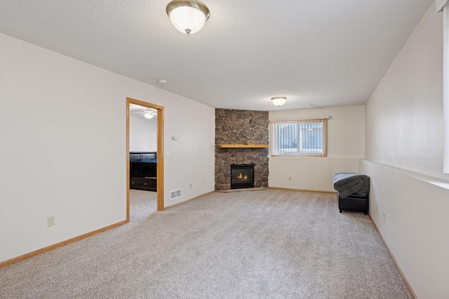 unfurnished living room featuring light colored carpet, visible vents, a textured ceiling, and a fireplace