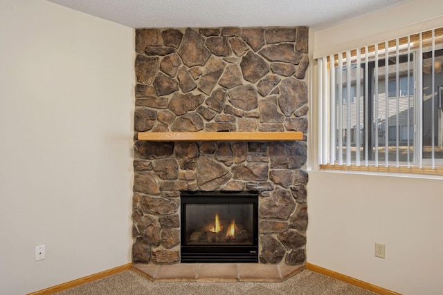 interior details with a stone fireplace, carpet flooring, a textured ceiling, and baseboards