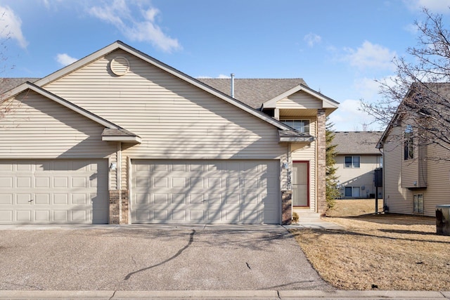 view of front of home featuring aphalt driveway, an attached garage, and brick siding