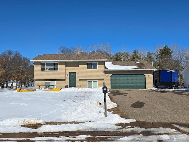 raised ranch with an attached garage and driveway