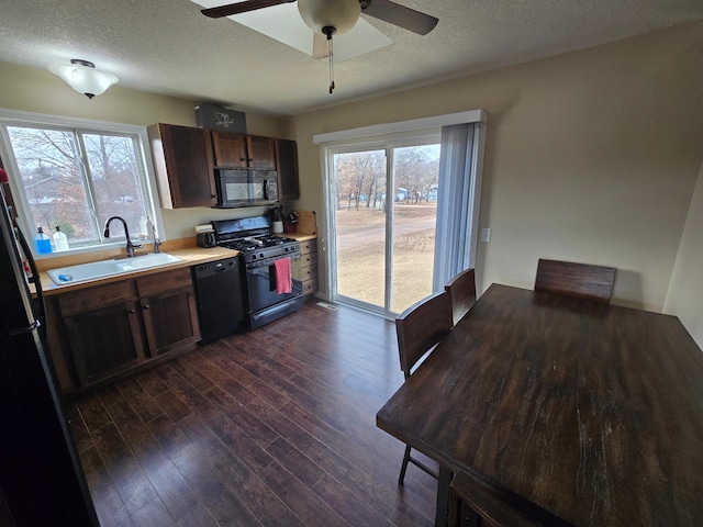 kitchen with dark wood finished floors, a textured ceiling, black appliances, and a sink