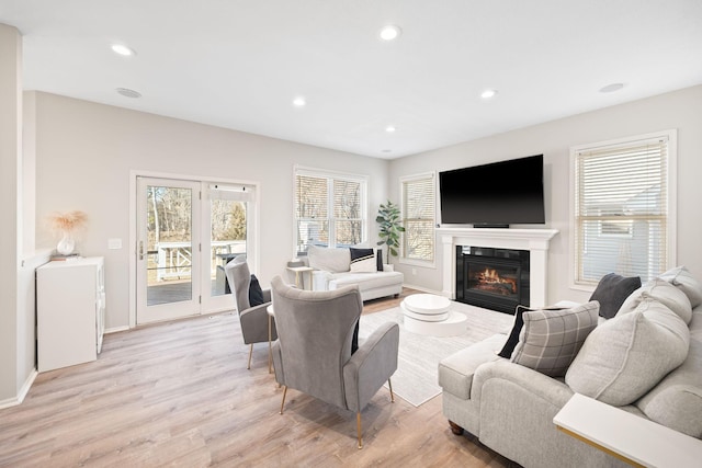 living area with a glass covered fireplace, light wood-style flooring, recessed lighting, and baseboards