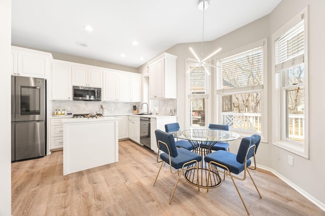 kitchen with a sink, stainless steel appliances, a kitchen island, and tasteful backsplash