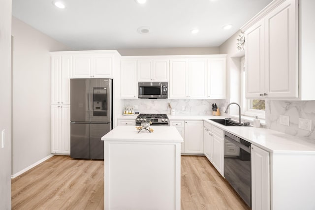 kitchen featuring light wood finished floors, backsplash, a kitchen island, appliances with stainless steel finishes, and a sink