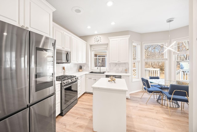 kitchen with tasteful backsplash, light countertops, appliances with stainless steel finishes, white cabinetry, and a sink