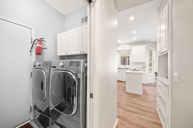 laundry area with visible vents, cabinet space, light wood-style floors, and independent washer and dryer