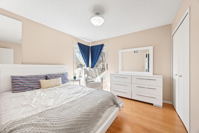 bedroom featuring light wood finished floors, a textured ceiling, and a closet