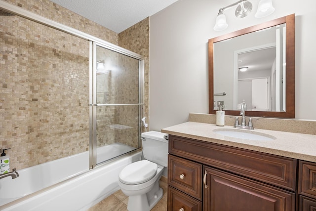 full bathroom with tile patterned flooring, bath / shower combo with glass door, toilet, vanity, and a textured ceiling