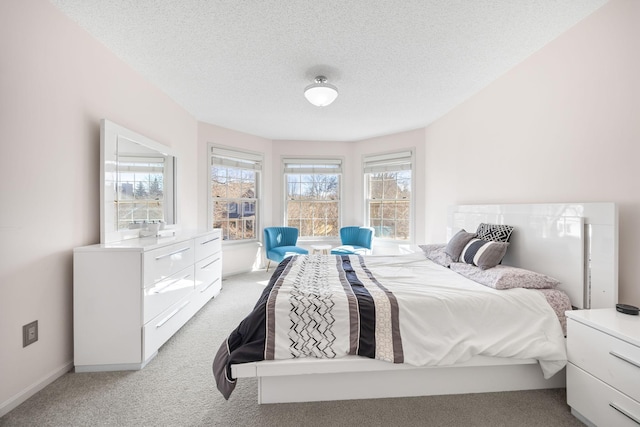 bedroom featuring light colored carpet, a textured ceiling, and baseboards