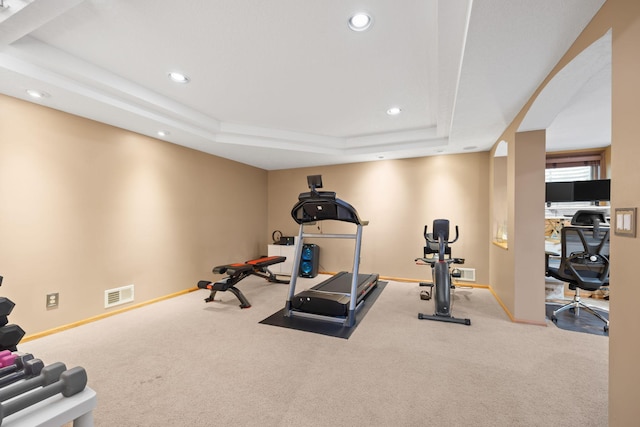 workout room with visible vents, a raised ceiling, and baseboards