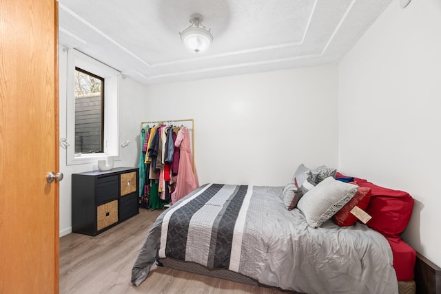 bedroom featuring a raised ceiling and light wood-type flooring