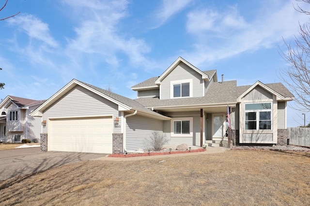 traditional home featuring driveway, fence, a shingled roof, a garage, and brick siding