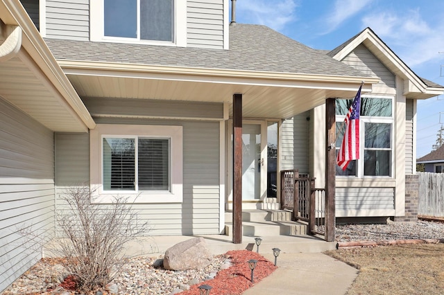 entrance to property featuring a porch and roof with shingles