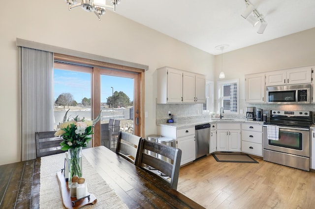 kitchen featuring backsplash, light wood-type flooring, white cabinets, stainless steel appliances, and a sink