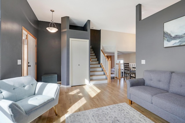 living room featuring light wood-style flooring, stairs, and baseboards