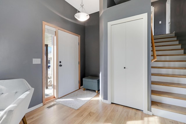 entryway with visible vents, a healthy amount of sunlight, stairway, and wood finished floors