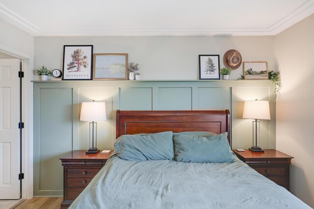 bedroom with a decorative wall and wood finished floors