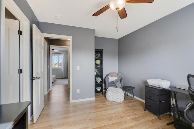 home office featuring light wood-style flooring, baseboards, and a ceiling fan