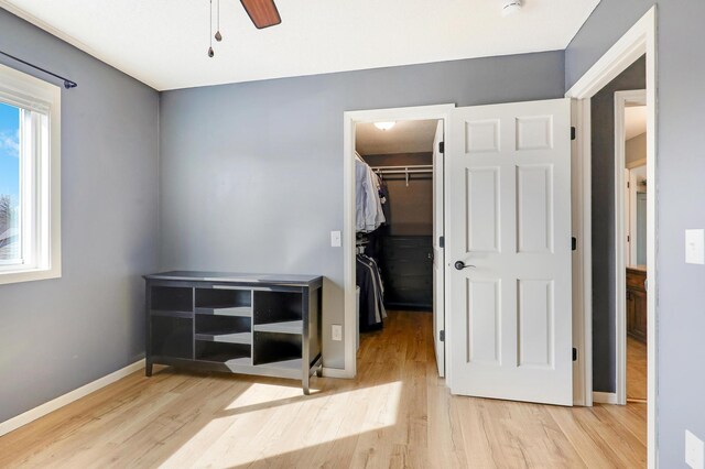 bedroom with a walk in closet, wood finished floors, a closet, and baseboards