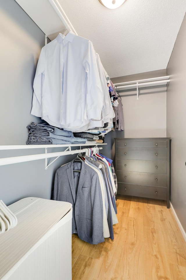 walk in closet with light wood-style floors