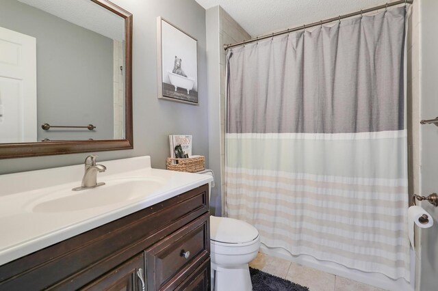 bathroom featuring toilet, shower / tub combo with curtain, a textured ceiling, tile patterned flooring, and vanity