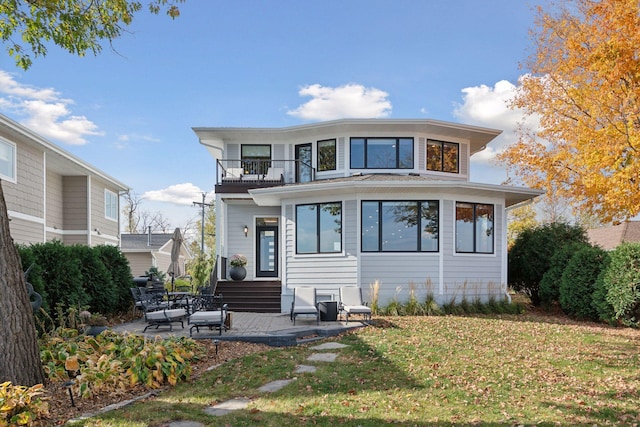 back of house featuring a balcony, a patio area, entry steps, and a yard