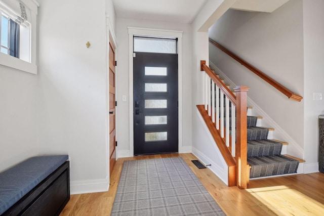 entrance foyer featuring light wood-style floors, visible vents, baseboards, and stairs