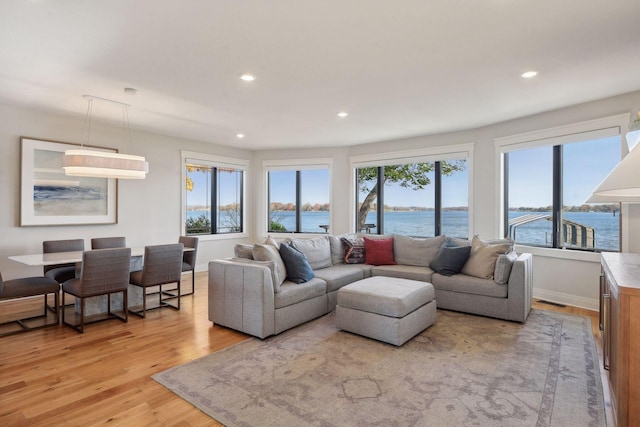 living area featuring visible vents, baseboards, light wood-style flooring, a water view, and recessed lighting