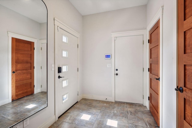 foyer entrance featuring stone finish floor and baseboards