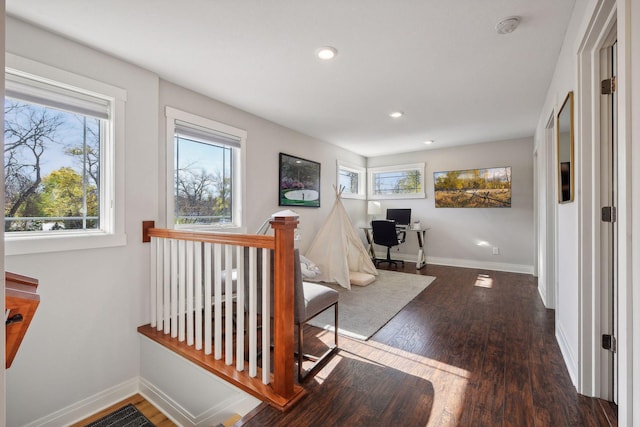 hall with an upstairs landing, baseboards, wood finished floors, and recessed lighting