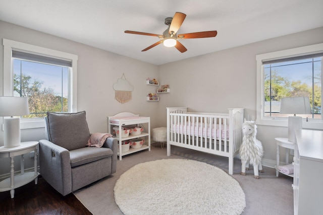 bedroom with a nursery area, ceiling fan, multiple windows, and baseboards